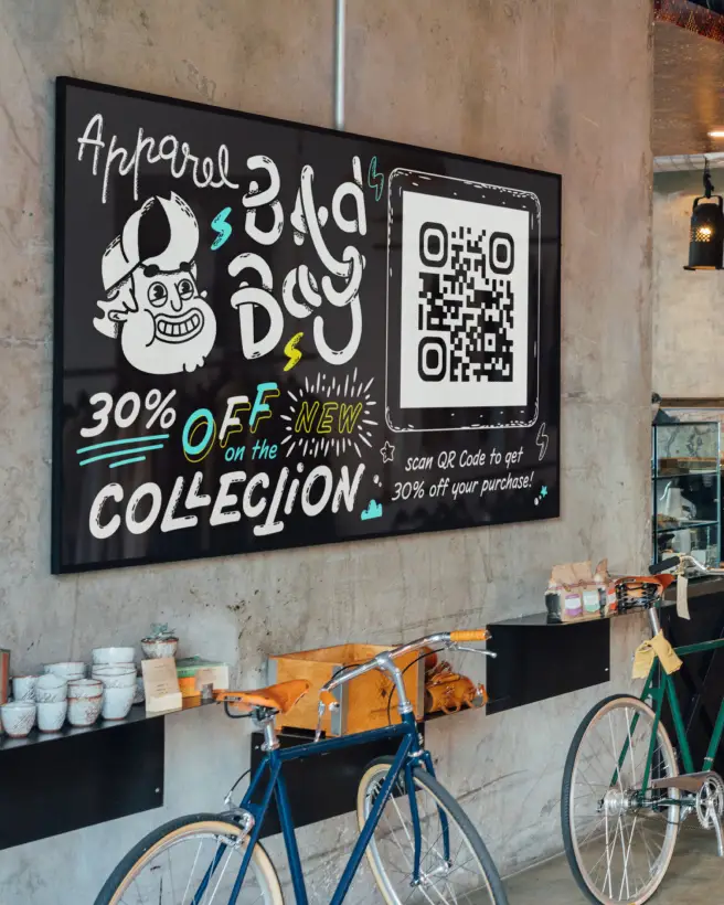 Retailer's black advertisement board hanging on a wall with white writing prompting to scan the QR Code for a discount.