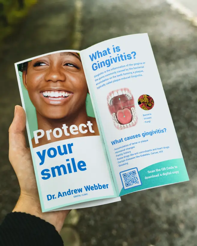 Hand holding a dentist's brochure about protecting your smile. There's a QR Code in the bottom-left corner to download a digital copy.