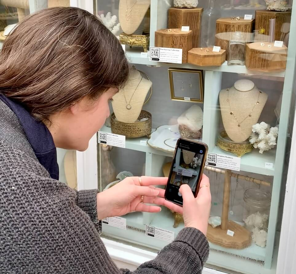 A woman scans a QR Code from a window display using her phone